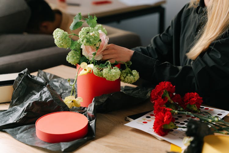 Person Arranging Flowers On A Wooden Table