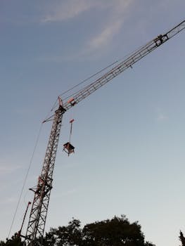 Tower crane operating at a construction site in Bottrop, Germany under a clear blue sky.