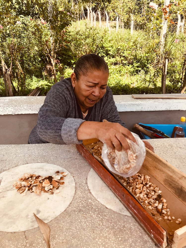 Woman Putting Breadcrumbs Into A Wooden Trough