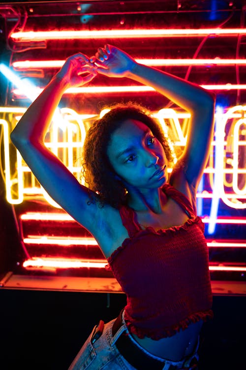 Photo of a Girl with Curly Hair Posing with Her Hands Above Her Head