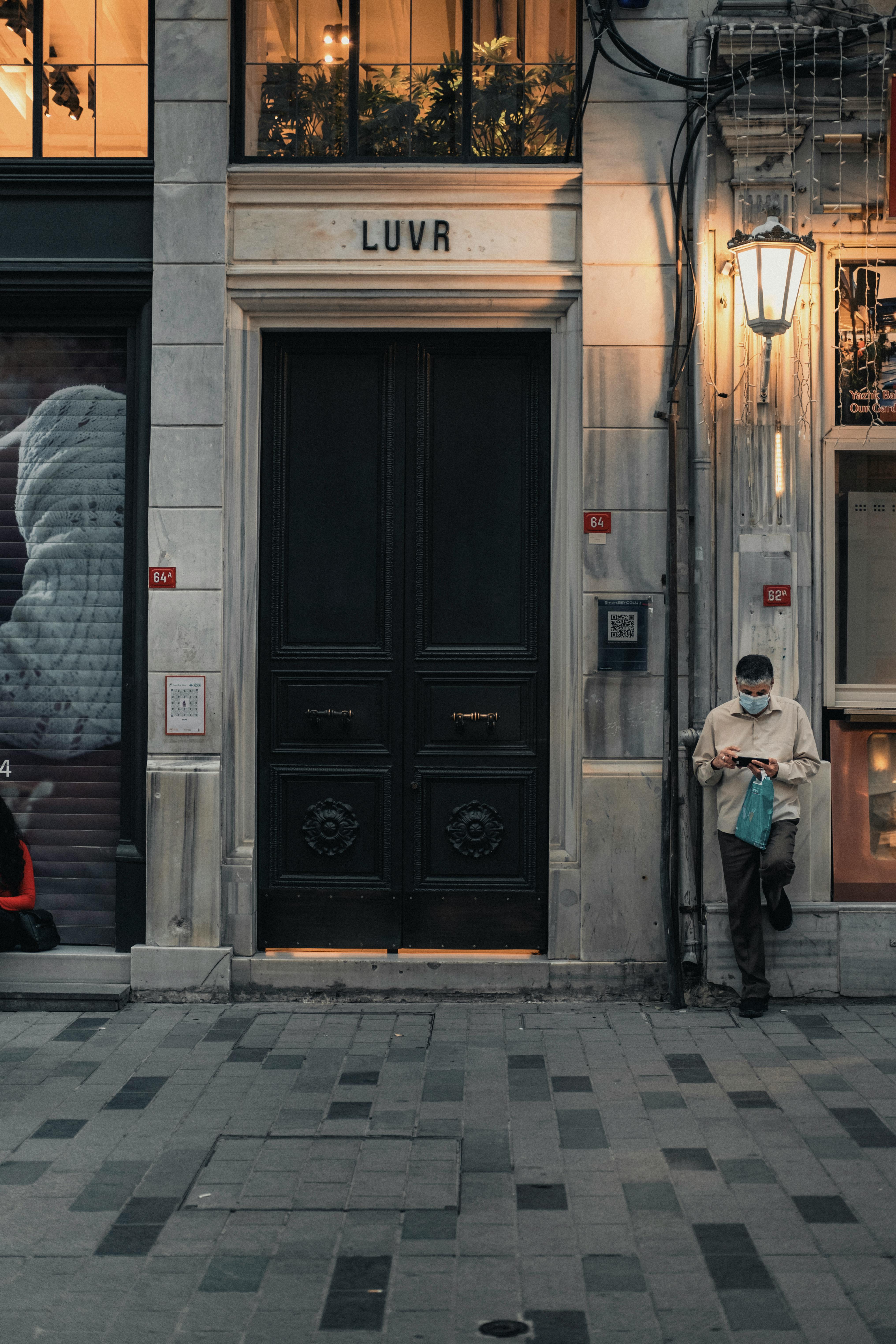 Anonymous male in casual clothes standing near entrance of stone building in evening time