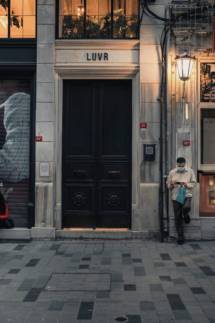 Unrecognizable Man Standing Near Old Door On Street