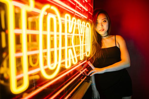 A Woman in a Spaghetti Strap Dress Leaning on a LED Signage