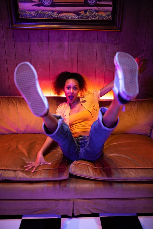 Free A Woman in Denim Jeans Sitting on the Couch while Raising Her Feet Stock Photo