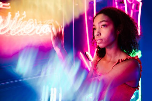 Woman in Red Tank Top Touching a Neon Signage