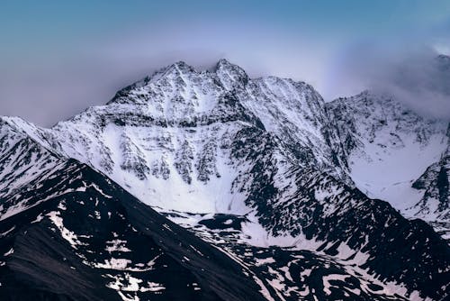 Snow Covered Dark Mountain Peak Under Foggy Sky