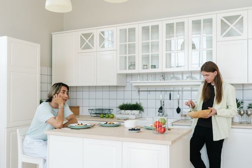 Free Two men in a stylish kitchen, preparing and enjoying a casual meal together. Stock Photo