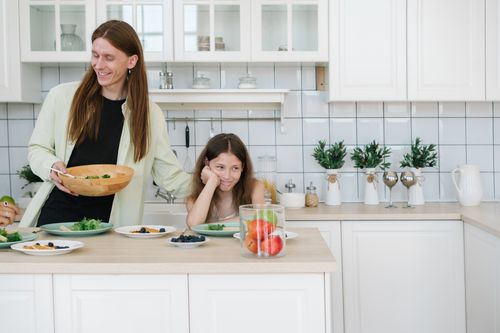 Free Father and daughter enjoying breakfast together in a modern kitchen setting, featuring fresh fruits and vegetables. Stock Photo
