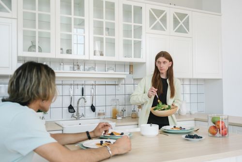Free Two people enjoying breakfast in a modern kitchen with a fresh salad and fruits. Stock Photo