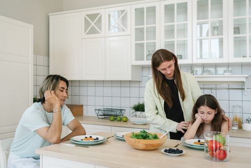 Free Family sitting around the kitchen table, sharing a meal in a modern setting. Stock Photo