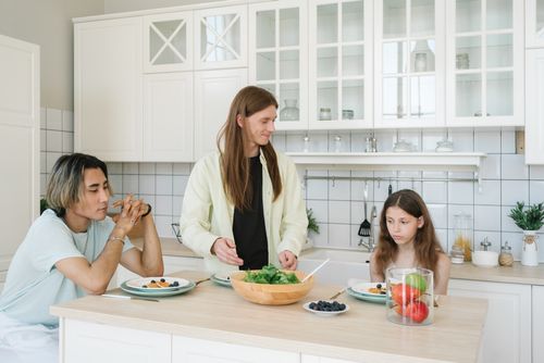 Free Family having breakfast together in a modern kitchen setting, showing connection and healthy eating. Stock Photo
