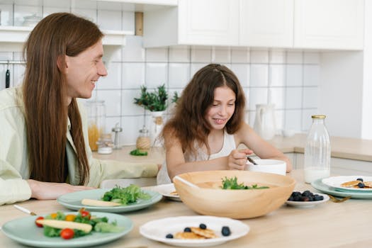 Father and daughter sharing a joyful breakfast at home in the kitchen.