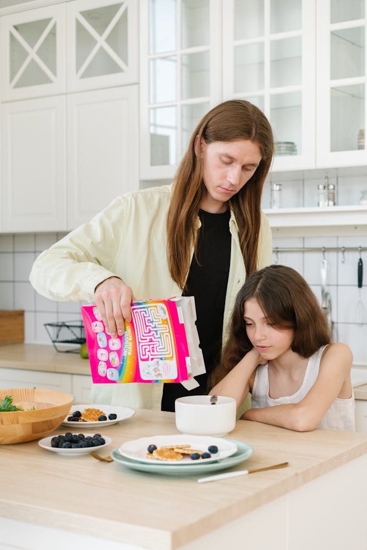 A Man Pouring Cereal For Her Daughter