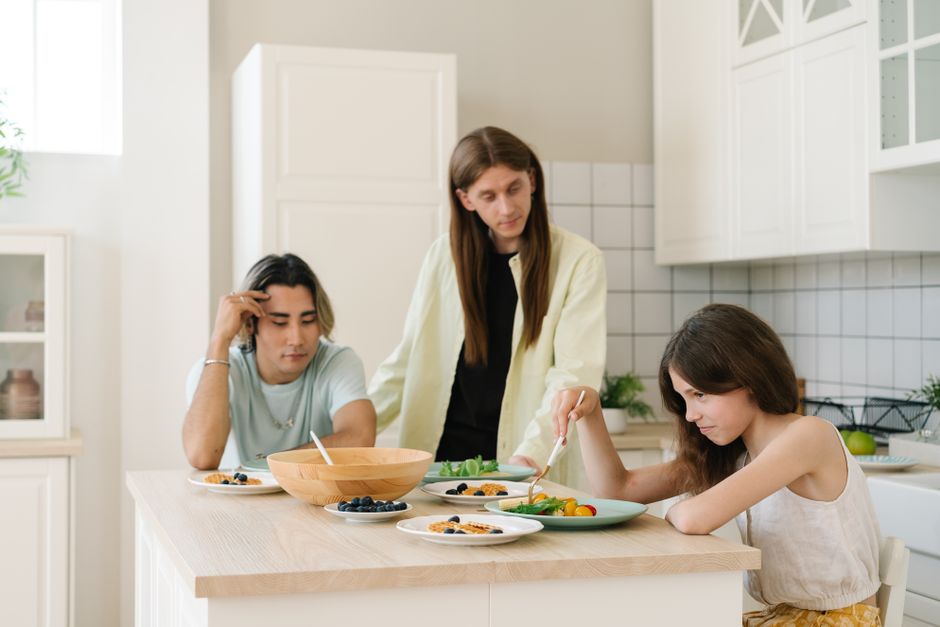 Una familia de tres disfrutando del desayuno juntos en una cocina moderna y luminosa.