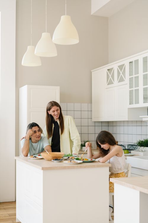 Free A cheerful family enjoys a meal together in a modern, bright kitchen setting. Stock Photo
