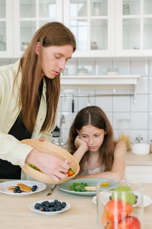 Free Father and daughter in kitchen preparing breakfast with fruits and waffles. Capturing family bonding time. Stock Photo