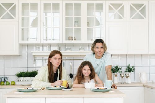 Free Smiling family enjoying breakfast together in a stylish modern kitchen setting, fostering warmth and connection. Stock Photo