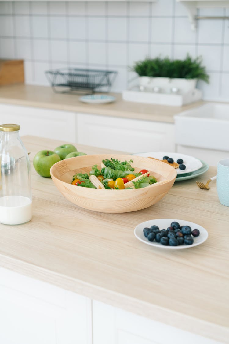 Salad On A Wooden Bowl And Blueberries On A Saucer