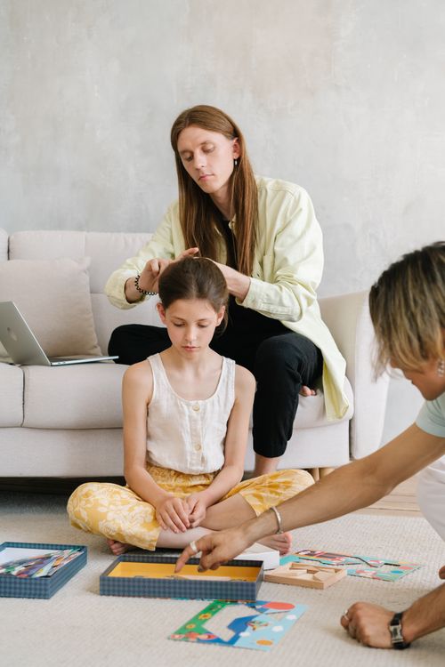 Free A family enjoying quality time, engaging in puzzle games and hair styling. Stock Photo