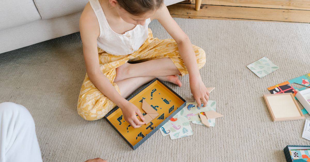 Jeune fille assise sur le sol créant des origami. Des couleurs et motifs vifs améliorent la scène artistique.