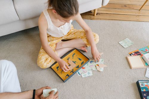 Free Young girl sitting on floor creating origami. Bright colors and patterns enhance the artistic scene. Stock Photo