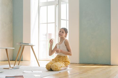Free Young girl playing on a carpet indoors, enjoying a sunny day with papers and books around. Stock Photo