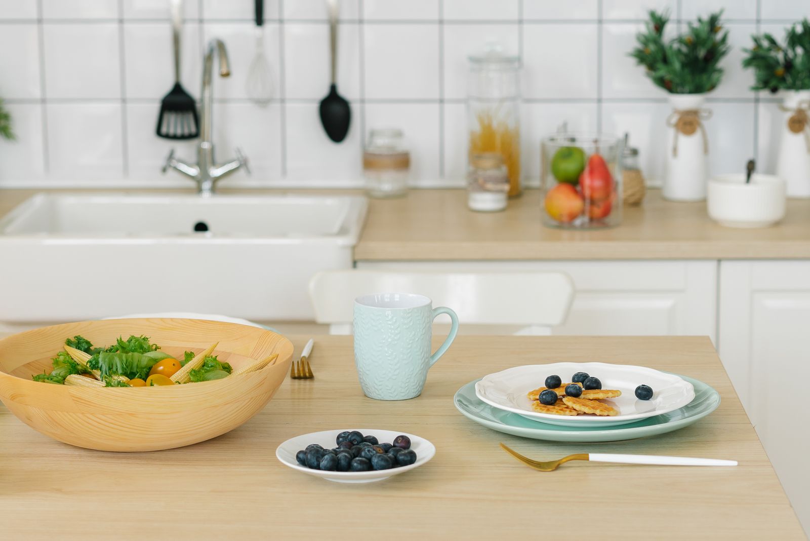 Bright kitchen setup featuring waffles, blueberries, and a fresh salad for a healthy breakfast.