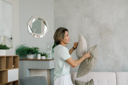 A Man in Crew Neck T-shirt Holding Throw Pillows