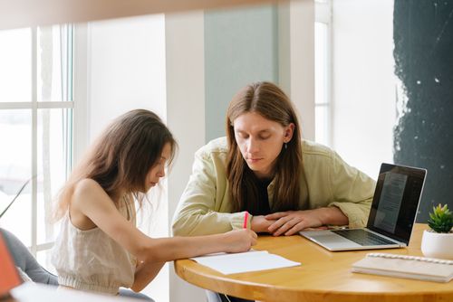 Free A father helps his daughter with homeschooling indoors, featuring a laptop and study materials. Stock Photo