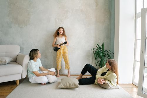 Free A family enjoys a relaxing moment at home with a girl playing the ukulele. Stock Photo