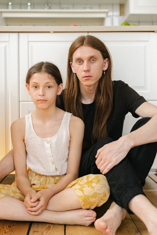 Free A Long Haired Man in Black Shirt Sitting Beside Her Daughter Stock Photo
