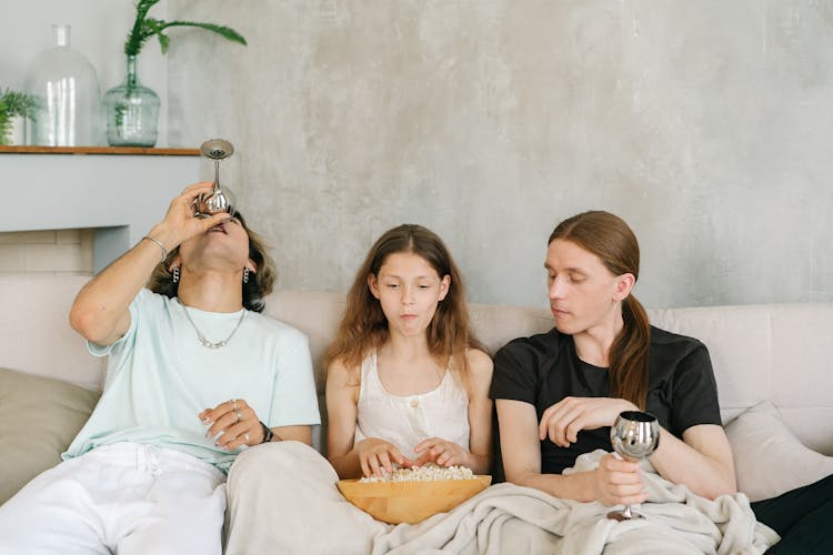 A Family Drinking And Eating On A Couch