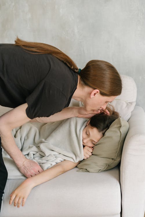 Free A Man in Black Shirt Kissing His Daughter Sleeping on the Couch Stock Photo