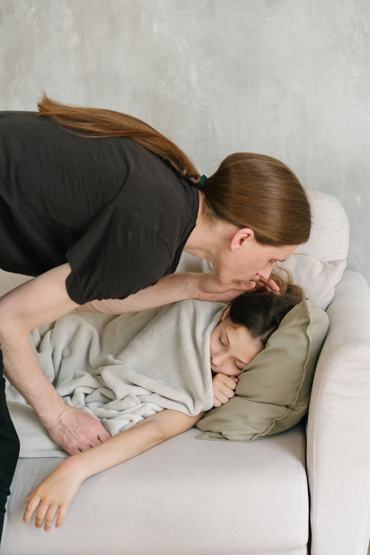 A Man In Black Shirt Kissing His Daughter Sleeping On The Couch