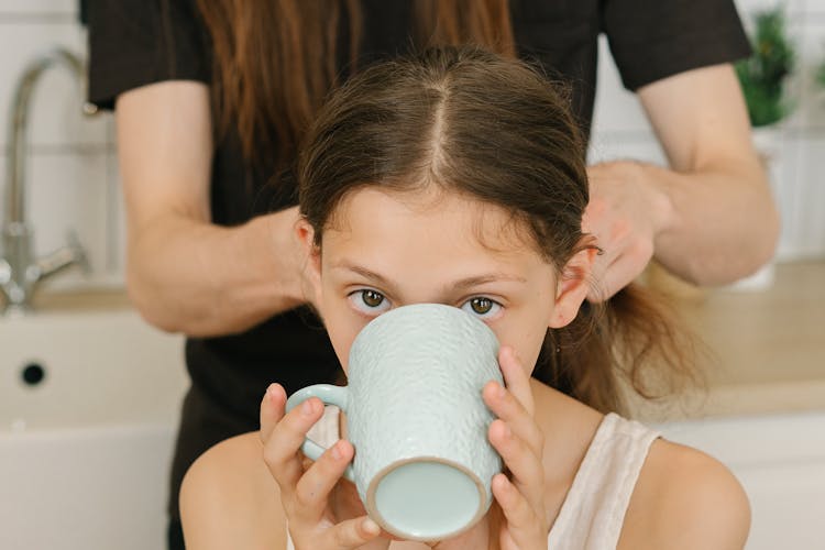 A Girl Drinking From A Ceramic Cup