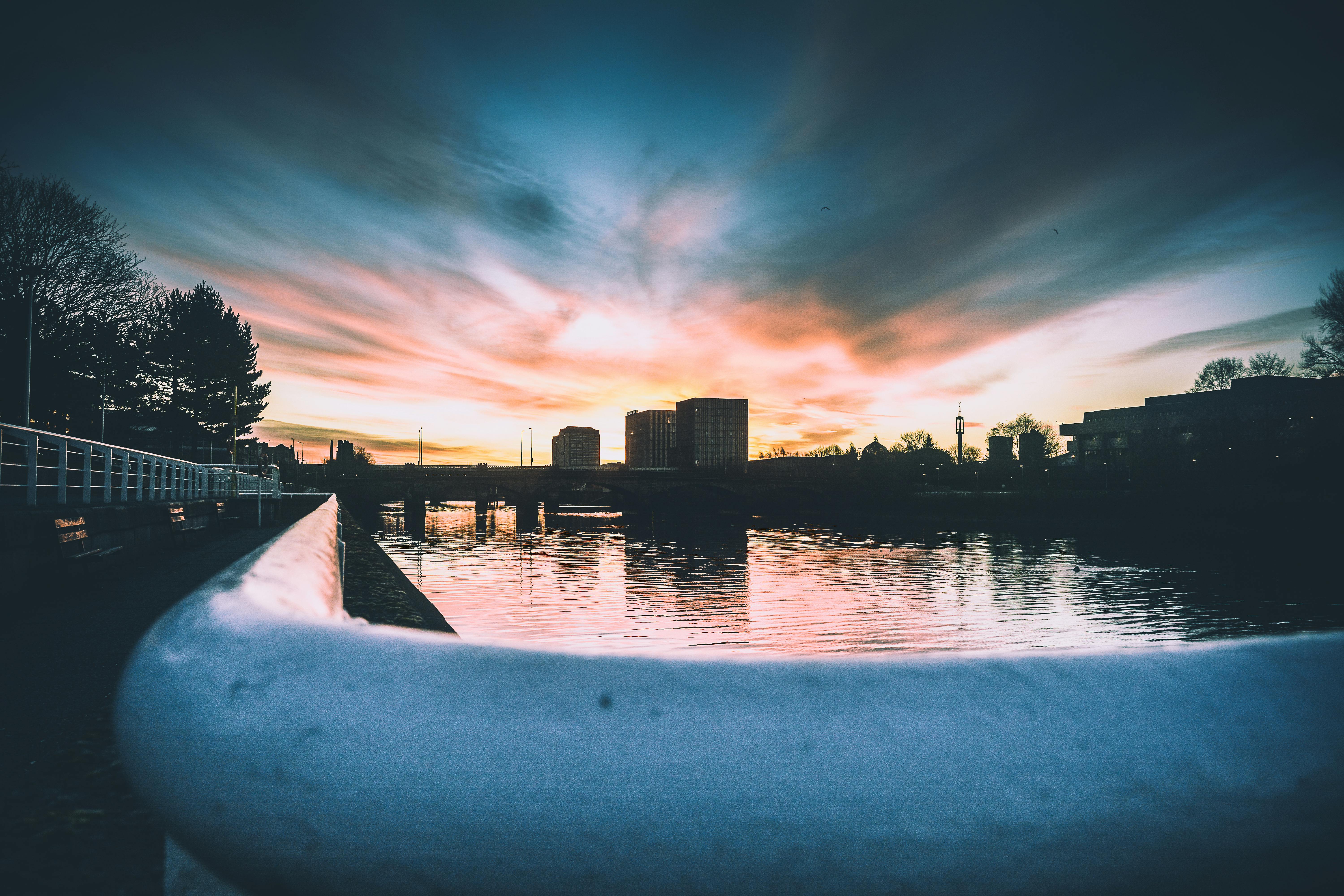 城市天际线上，令人惊叹的日落投射出充满活力的色调，倒映在宁静的河水中