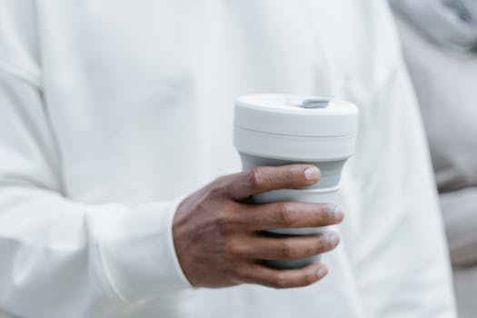A close-up view of a hand holding a collapsible, reusable silicone cup.