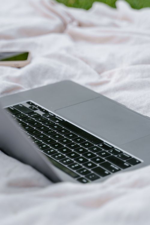 Free A detailed close-up of a laptop on a white blanket outdoors in a relaxed setting. Stock Photo