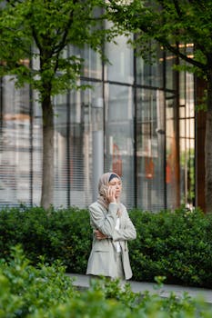 Businesswoman in hijab making a phone call outdoors in urban setting.