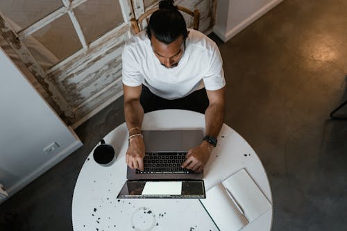 Free A Man Sitting at the Table while Using Laptop Stock Photo