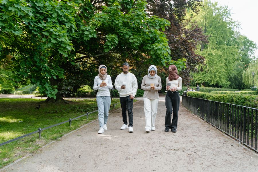 Friends walking together along a path in a green park, photo by MART PRODUCTION on Pexels