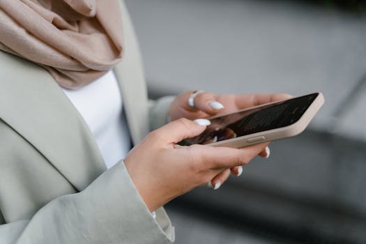 Businesswoman in gray suit checking smartphone messages outdoors.
