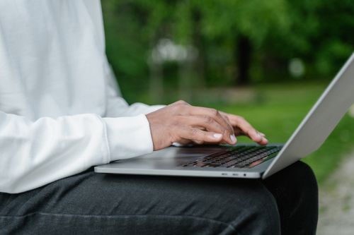 Free Close-up of hands typing on a laptop in a green park, highlighting outdoor work. Stock Photo