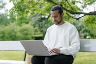 A Man in White Sweater Using a Laptop in the Park