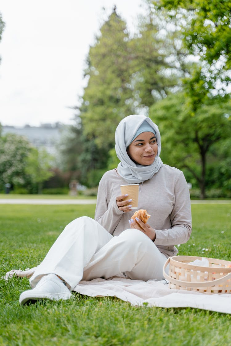 Woman In White Hijab Sitting On A Picnic Blanket On Park