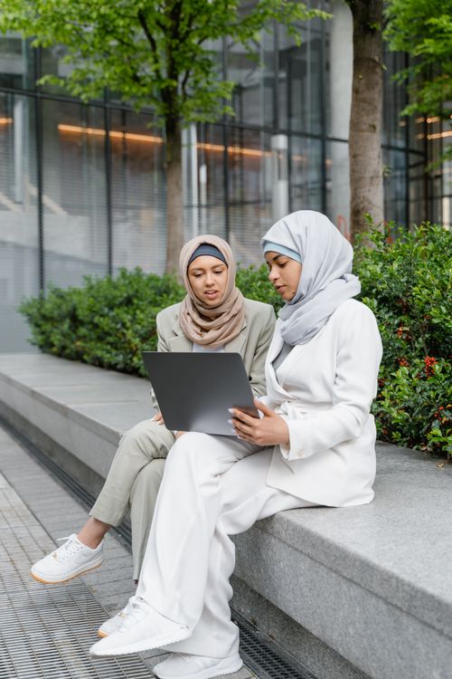 Free Two Muslim women in hijabs having a business meeting outside with a laptop. Stock Photo