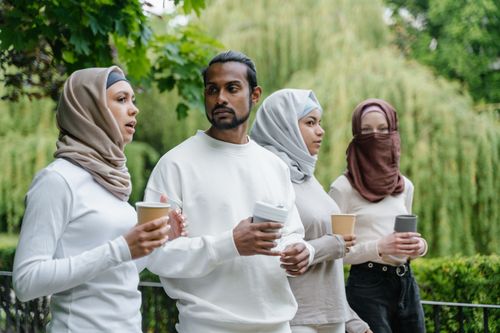 Free A group of friends with diverse backgrounds enjoying coffee together in a park setting. Stock Photo