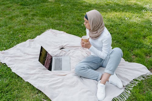 A Woman in Brown Hijab Sitting on the Grass