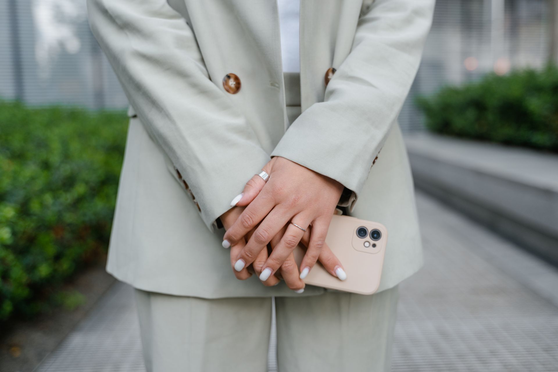Woman in Business Coat Holding a Smartphone
