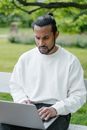 A Man in White Sweater Using a Laptop in the Park